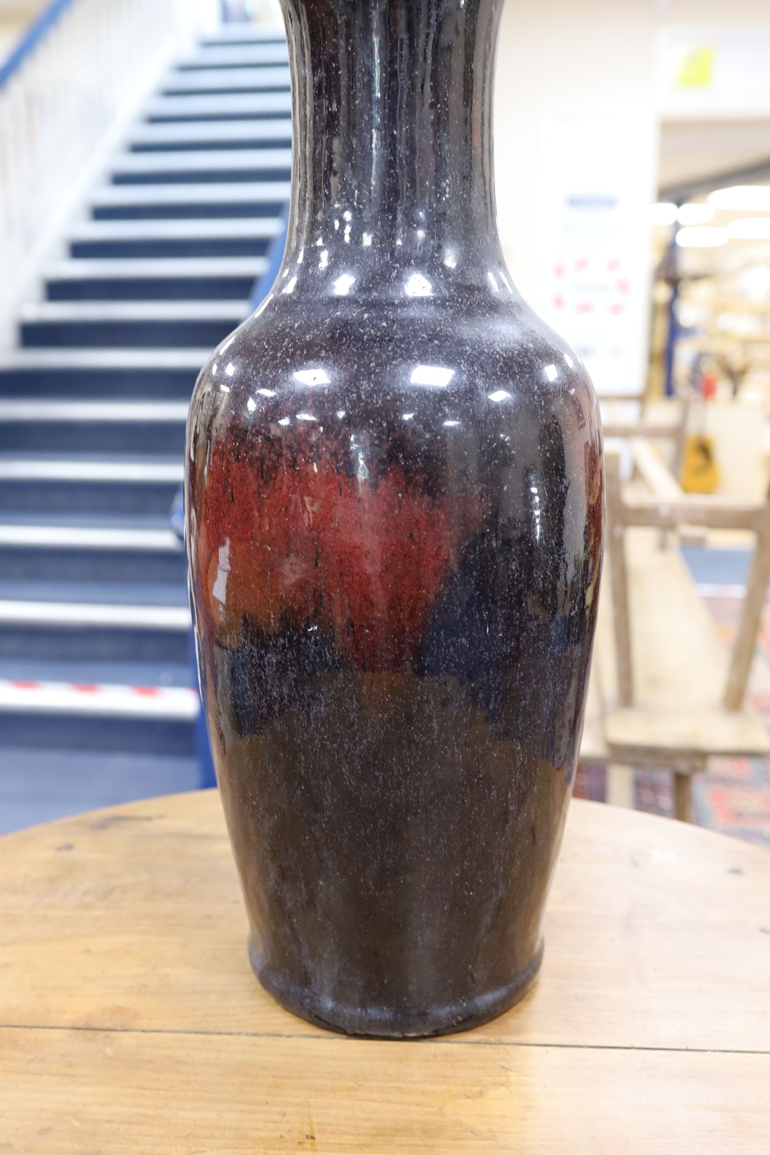 A large Chinese sang de boeuf glazed vase on carved wooden stand., Vase 61 cms high not including stand.